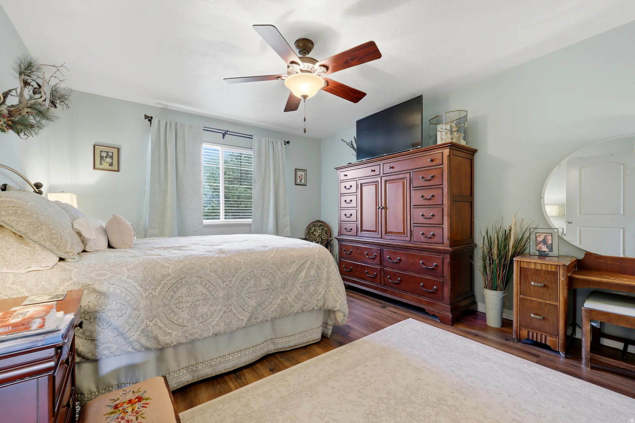Wood-finish flooring, ceiling fan with integrated lighting, and a single window with blinds