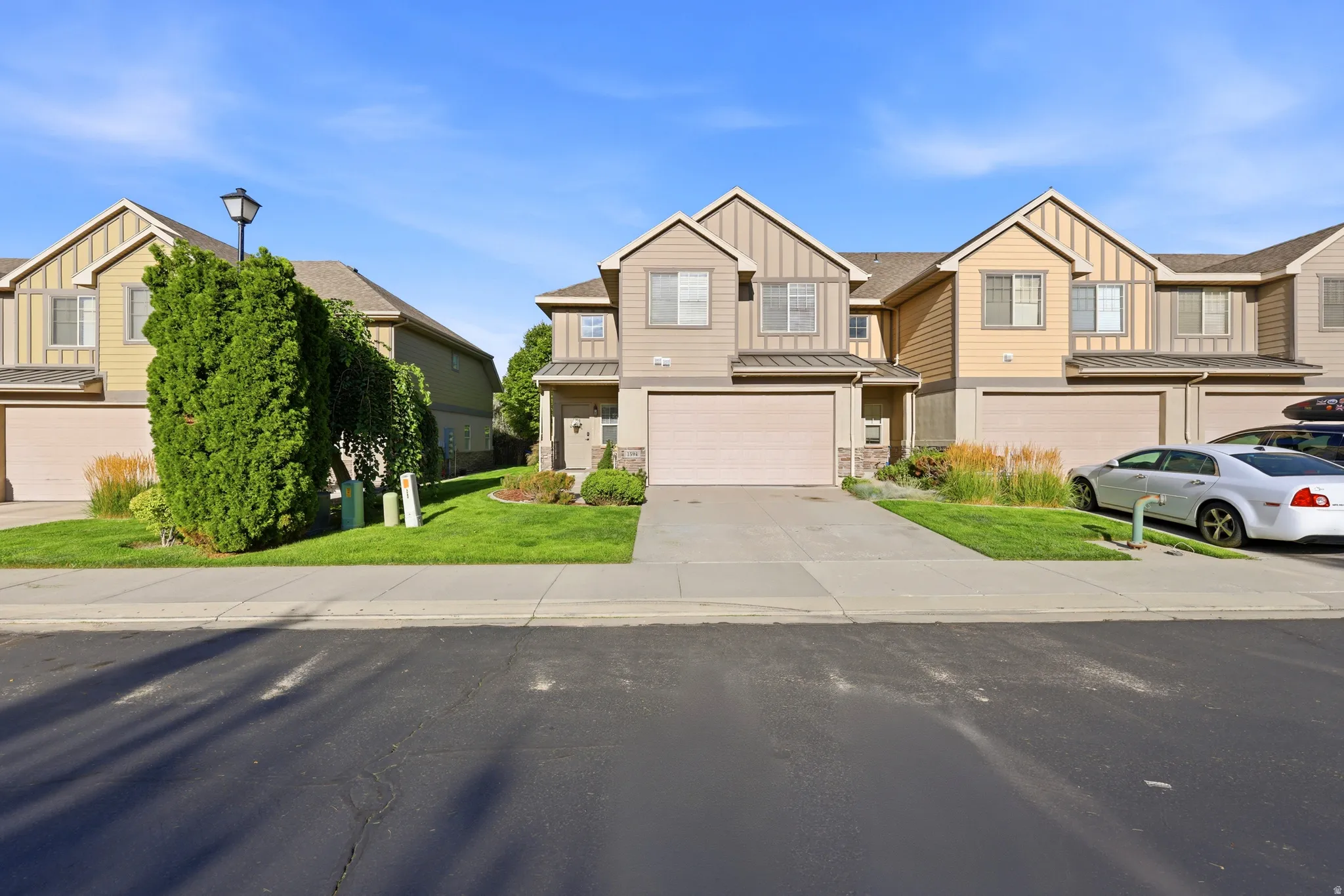 Townhome exterior featuring varied siding materials, attached garages, paved driveways, and landscaped front yards