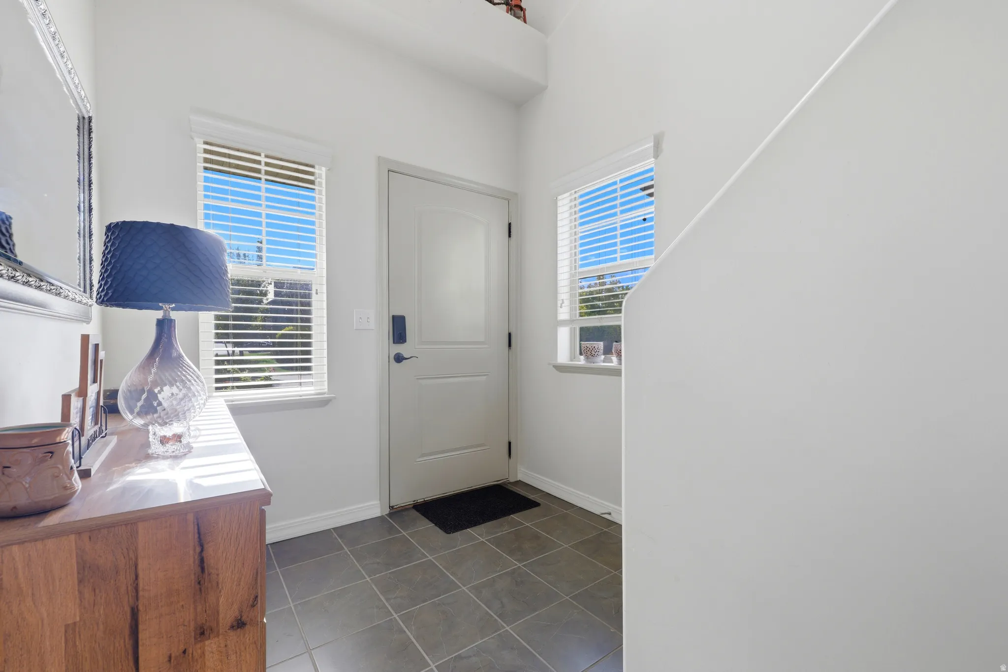 Entryway featuring tile flooring, a solid core entry door, and two windows with blinds