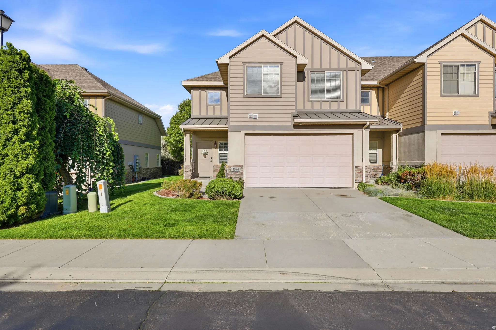 Light-toned siding exterior with stone accents, a concrete driveway, and a single-car garage