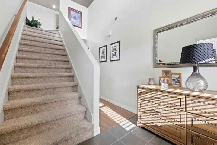 Carpeted staircase with a wood handrail, recessed lighting, and a wood-finish flooring transition