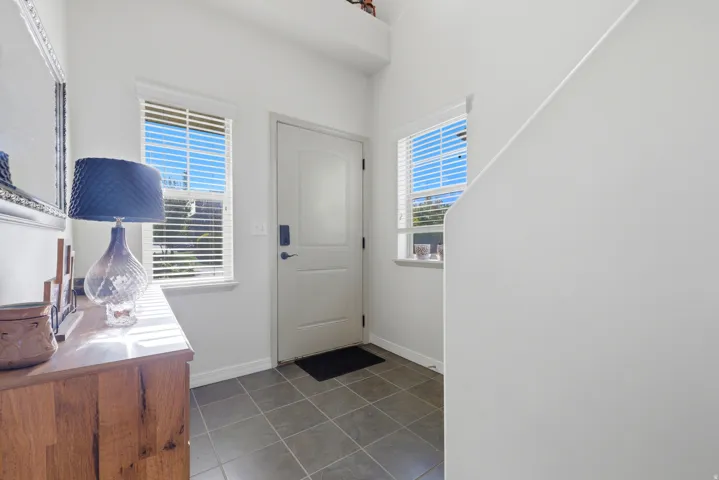 Entryway featuring tile flooring, a solid core entry door, and two windows with blinds