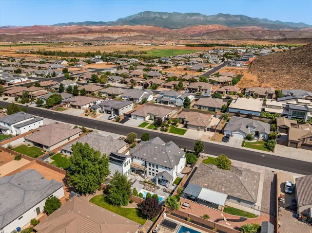 Aerial view showcasing a contemporary residence with a dark-toned roof, mature landscaping, and manicured grounds situated within an established residential community