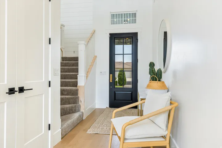 Bright entryway with wood-finish flooring, white shiplap walls, and black-framed glass entry door with transom window