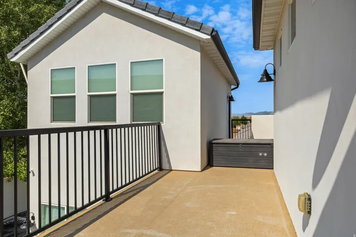 Spacious composite deck with composite wood-finish flooring, black metal railing, and access to a modern white exterior featuring triple casement windows and clean architectural lines