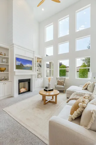 Two-story living area with a built-in fireplace, extensive window array, and integrated shelving