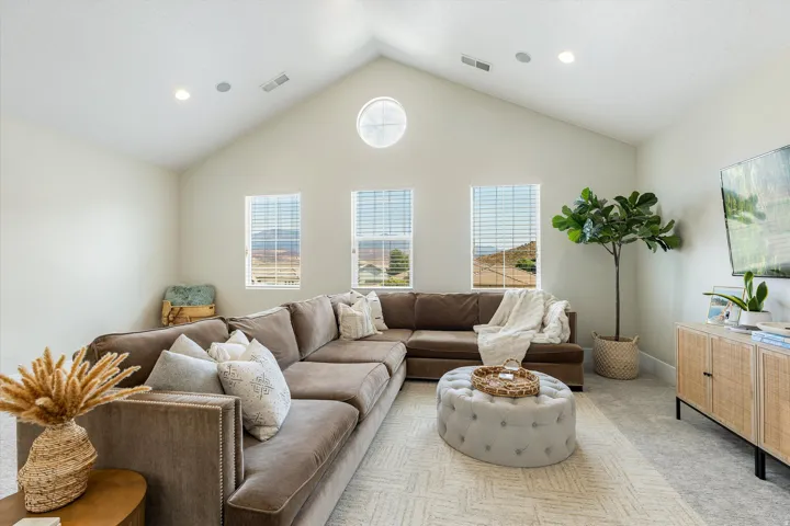 Bright, vaulted great room with cathedral ceiling and abundant natural light from three large windows and circular skylight