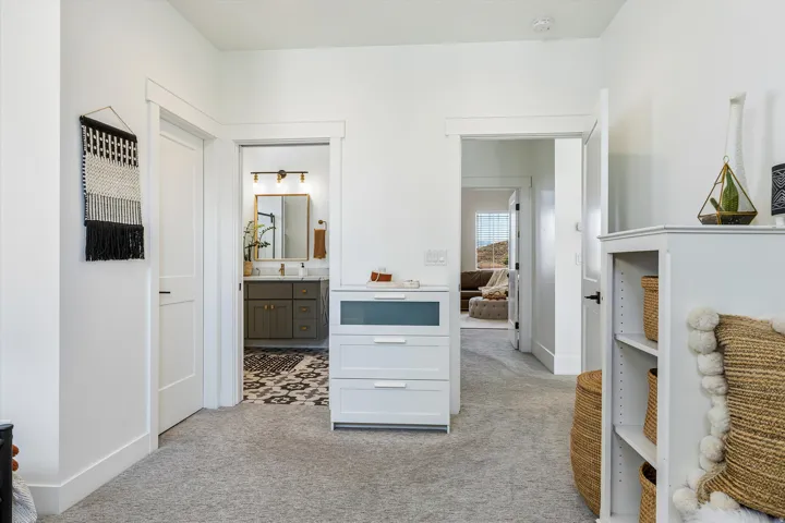 Primary bathroom and hallway featuring white shaker-style cabinetry, patterned tile flooring, quartz countertops, and soft-close drawers