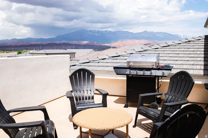 Rooftop entertaining space featuring multiple Adirondack seating, a built-in gas grill, and expansive mountain vistas
