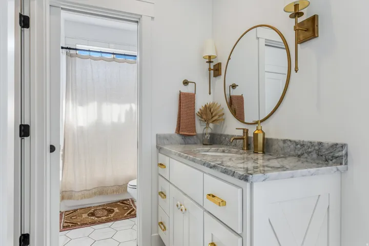 Vanity with stone countertop, integrated sink, and brass-finish faucet