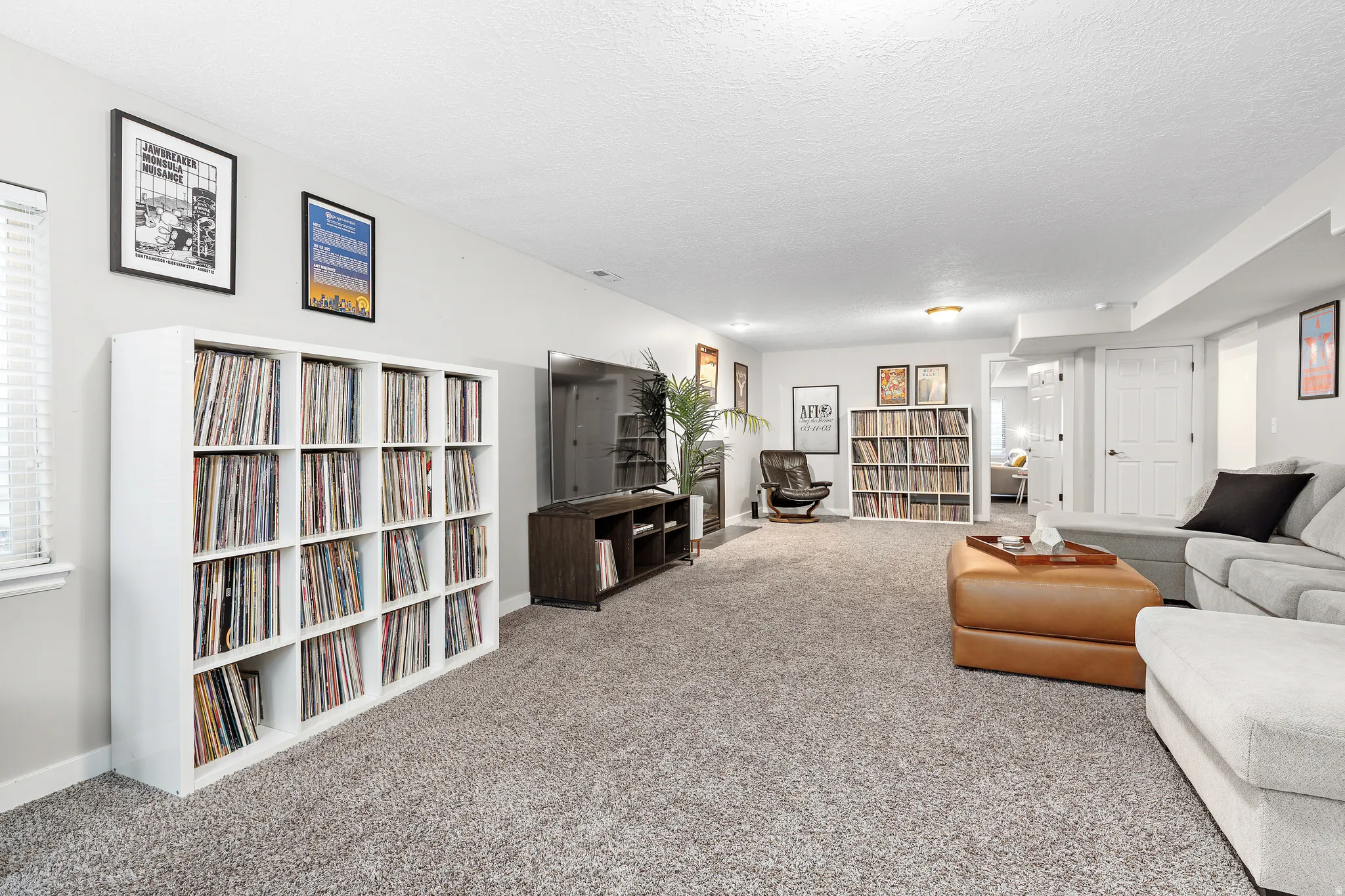 Recessed lighting illuminates a spacious room featuring light gray carpeting and white walls