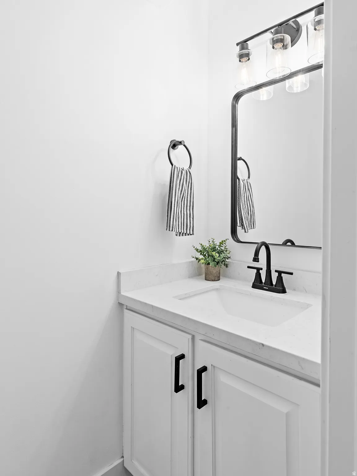 White vanity with shaker-style cabinet doors, matte black hardware, and integrated sink with a black faucet