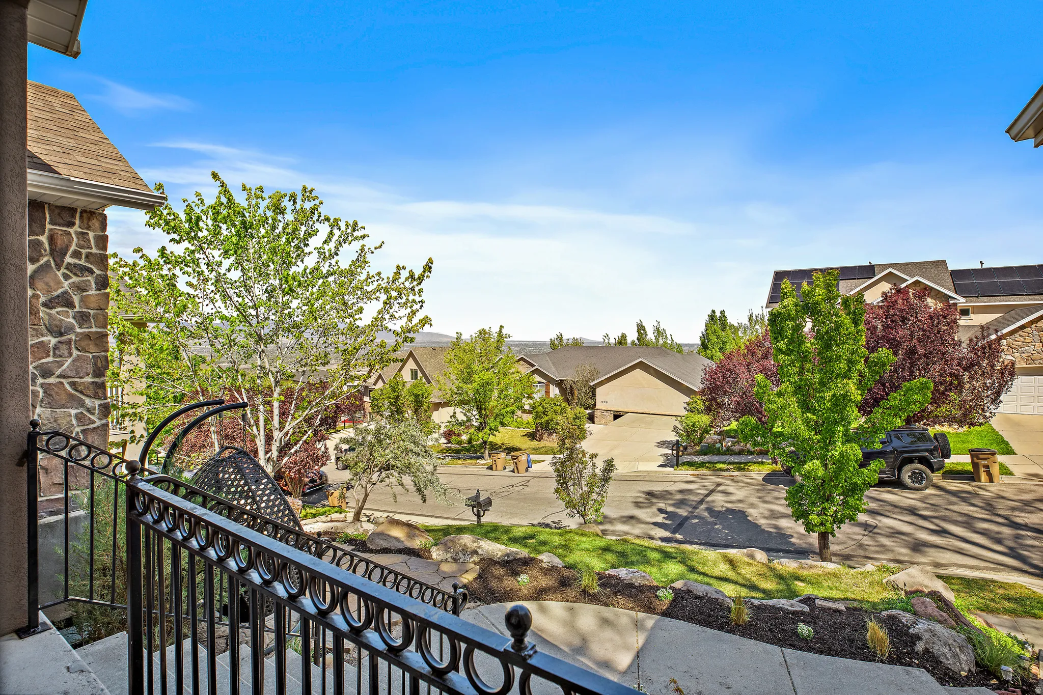 Elevated balcony with decorative metal railing overlooking a landscaped neighborhood setting