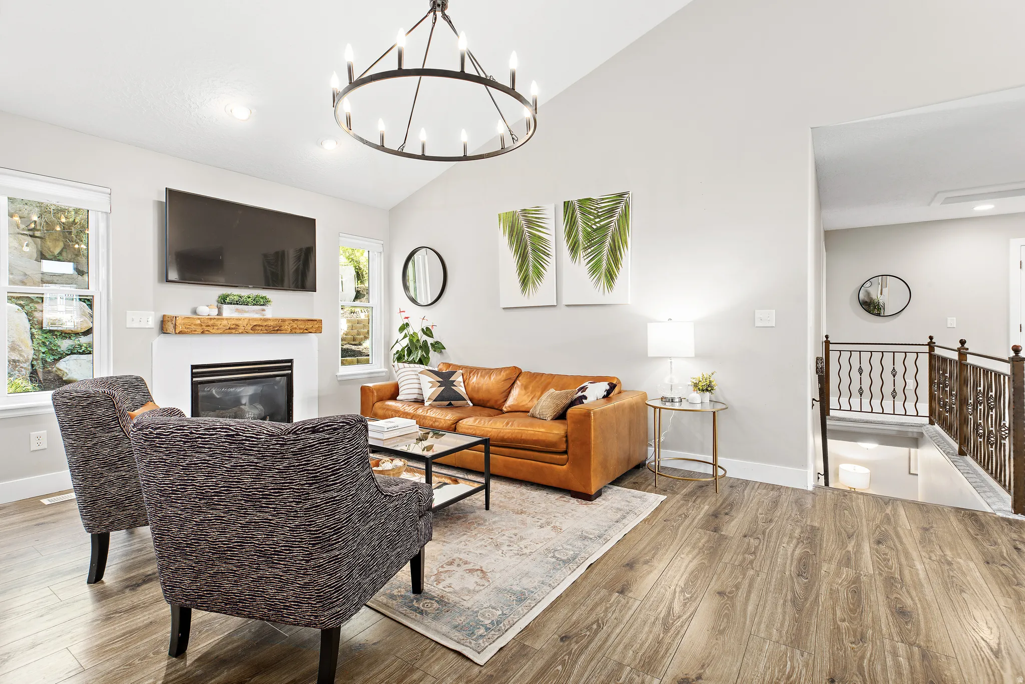 Bright, open-concept living area featuring a wood-finish plank floor, gas fireplace with built-in shelving, and an ornamental metal chandelier