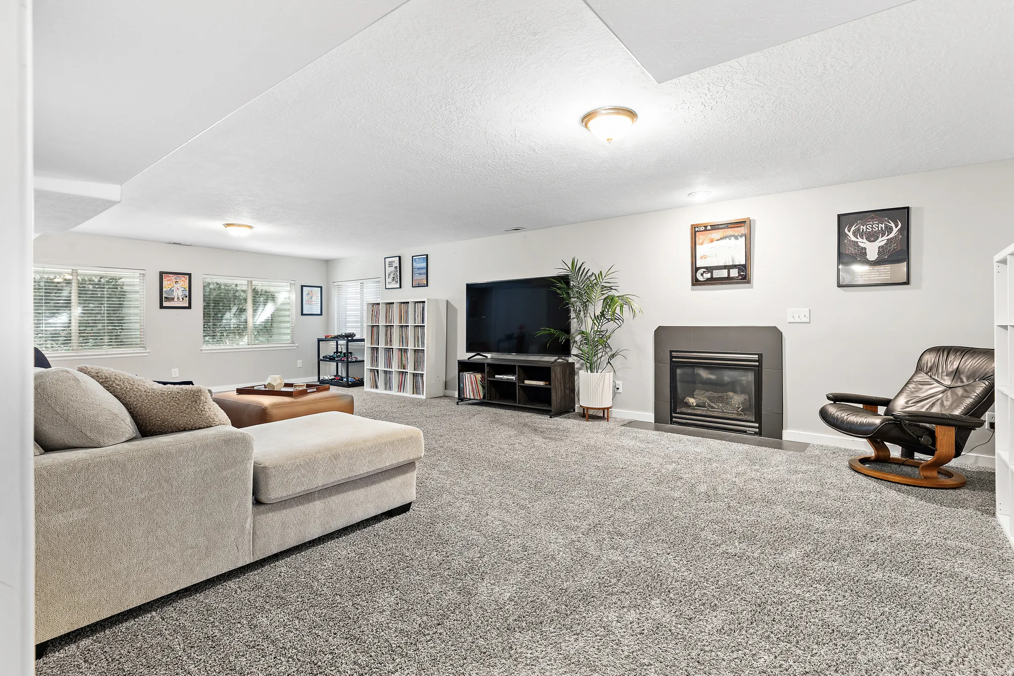 Spacious room with gray carpeting, multiple windows, and a built-in fireplace