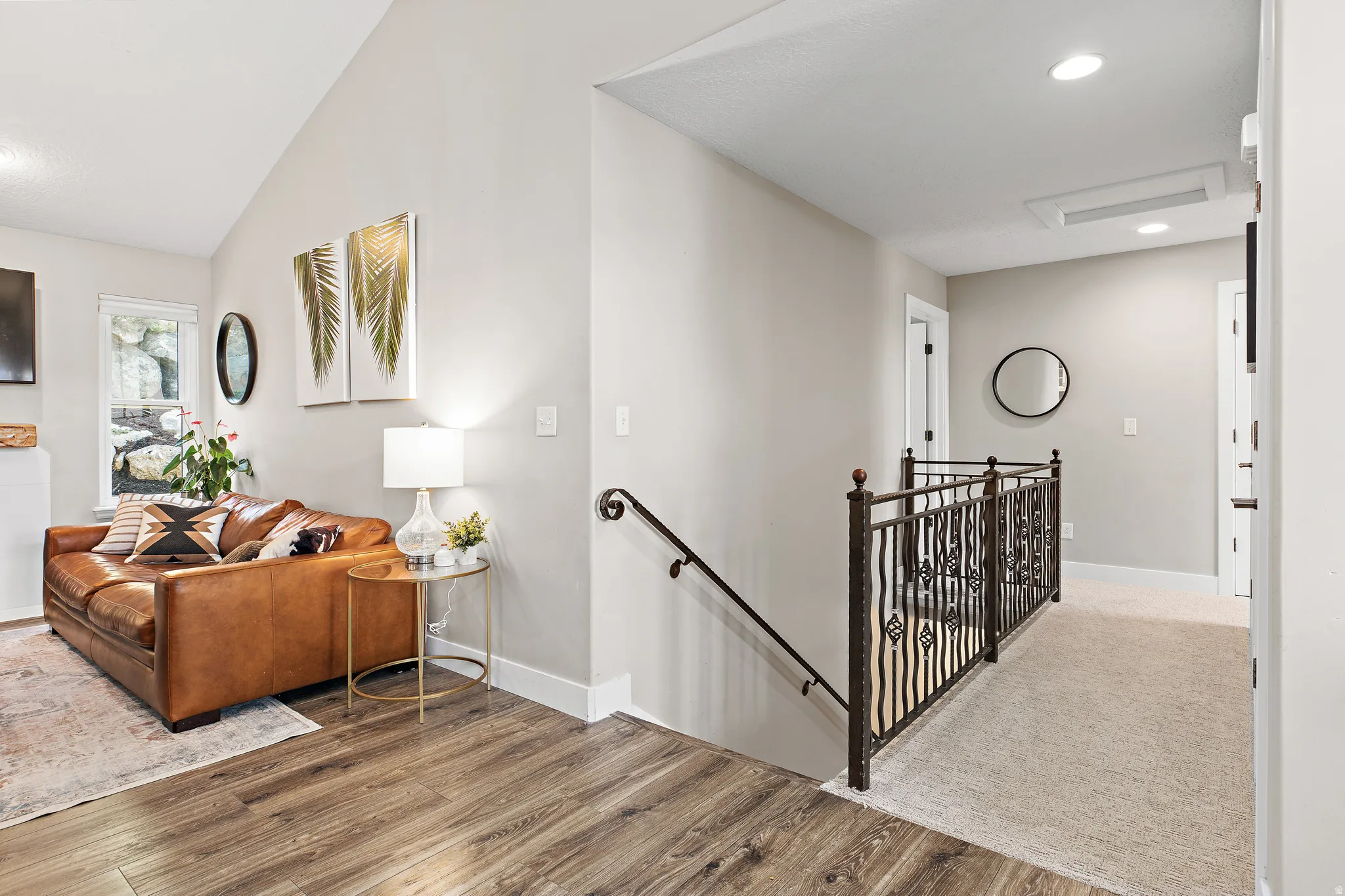 Vaulted ceiling with recessed lighting, wood-finish flooring, wrought iron railing, and neutral wall tones