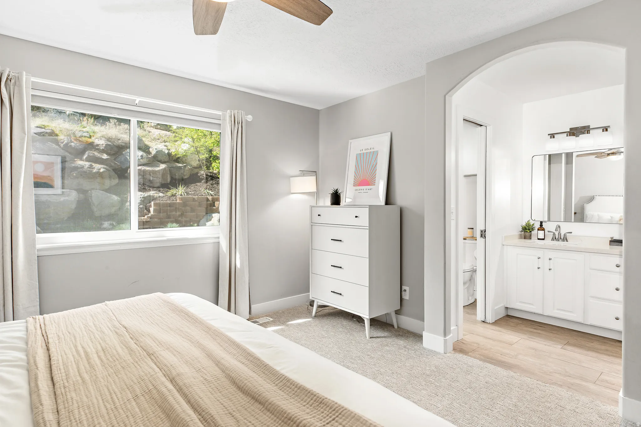 Archway entry to a bathroom featuring a vanity with white cabinetry, a rectangular mirror, and a wall-mounted light fixture