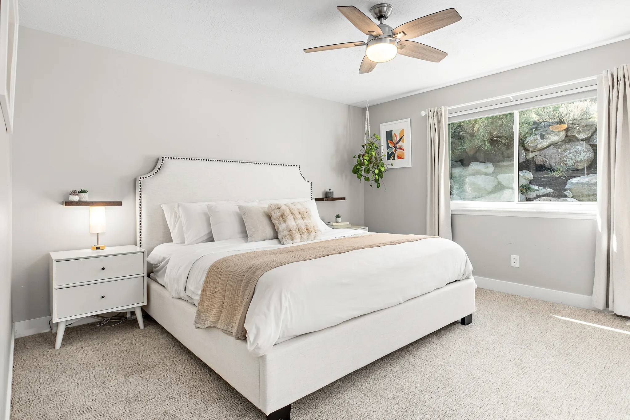 Serene primary bedroom showcasing a upholstered bed frame with nailhead trim, soft neutral bedding, and coordinating throw pillows