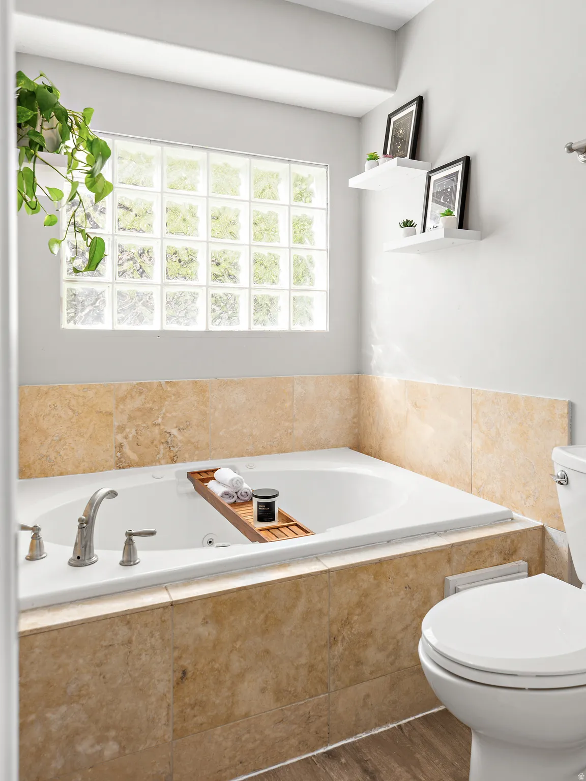 Deep-set soaking tub with deck-mounted chrome fixtures, surrounded by light-toned stone tile
