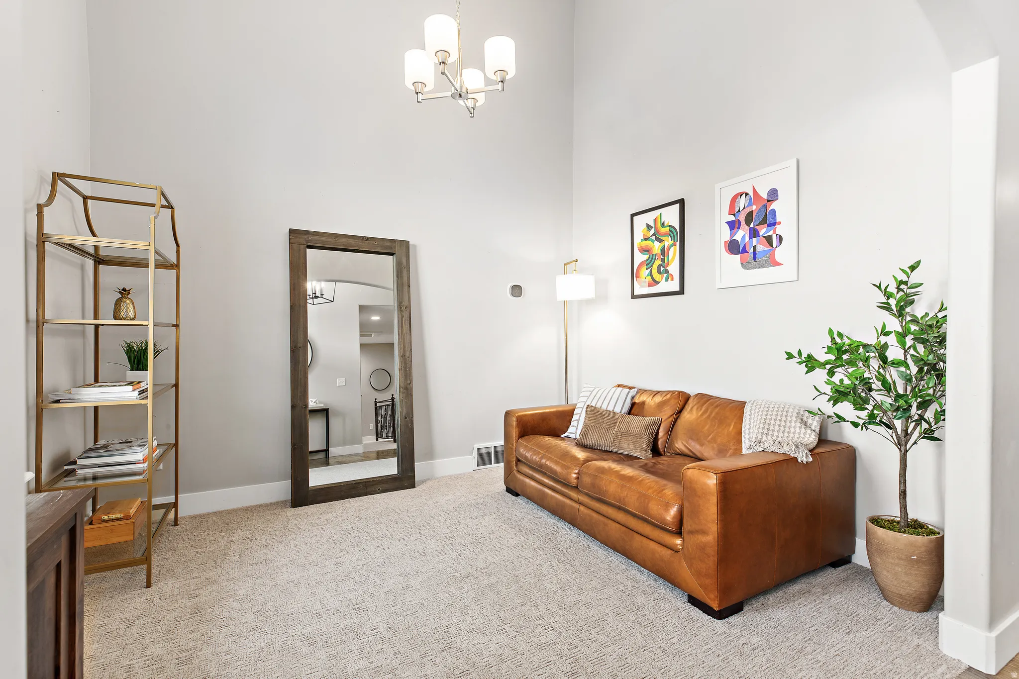 High ceilings with an elegant chandelier, neutral wall paint, and plush carpeting create a refined space
