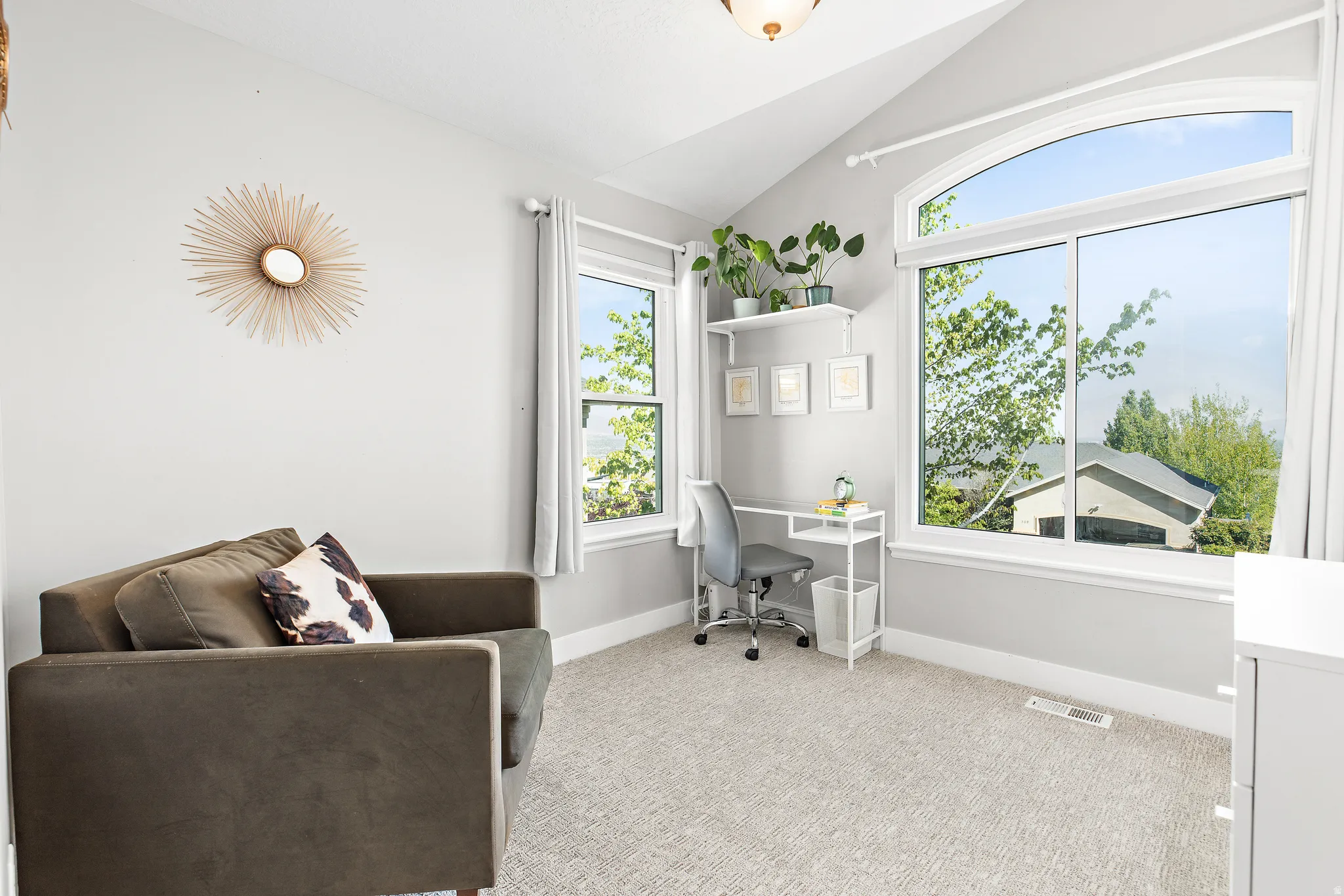Arch-top window, vaulted ceiling, built-in shelving, light gray wall finish, and carpeted flooring