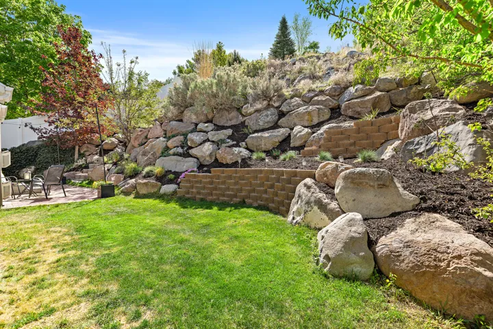 Expansive lawn area with a stone retaining wall and tiered landscaping