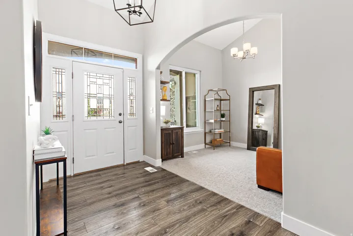 Entryway featuring wood-finish flooring, a decorative glass paneled door with sidelights and transom, and a high vaulted ceiling with a modern light fixture