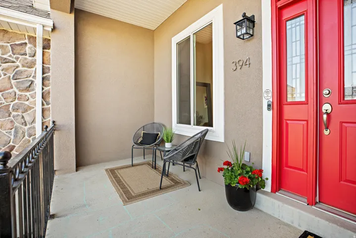 Entry with a vibrant red double door, sconce lighting, and decorative house numbers