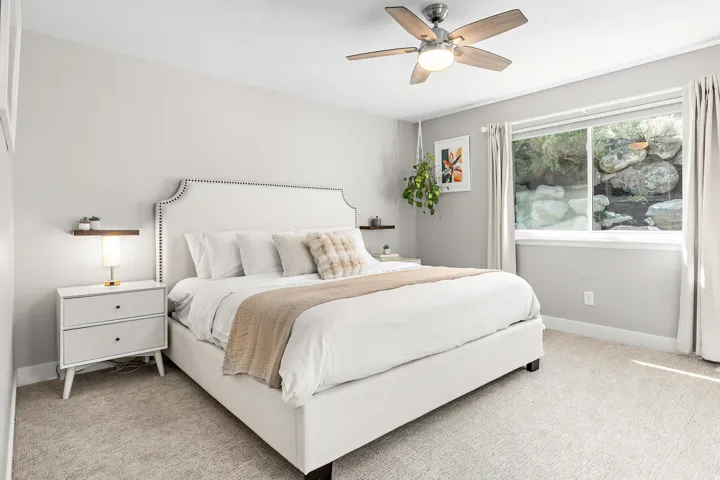 Serene primary bedroom showcasing a upholstered bed frame with nailhead trim, soft neutral bedding, and coordinating throw pillows