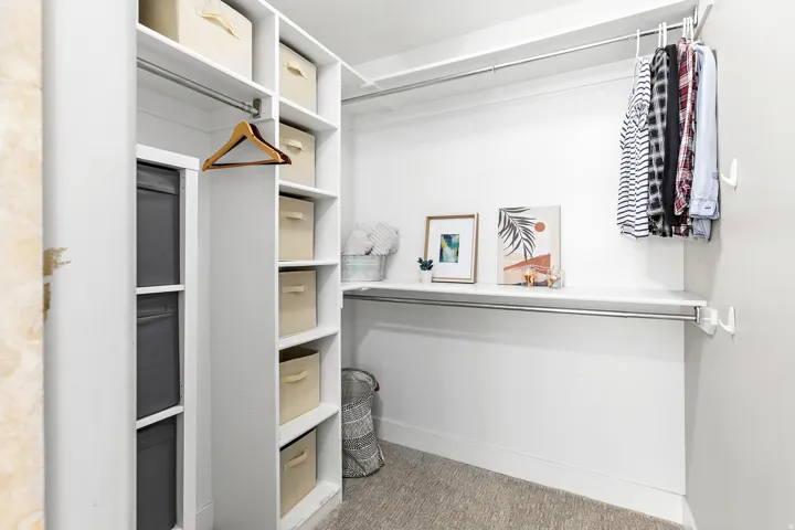 Custom closet system with white shelving, multiple storage compartments, and metal hanging rods