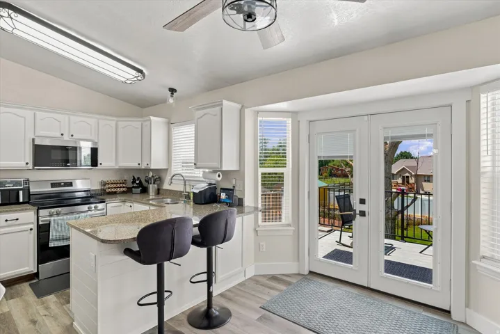 Kitchen featuring white cabinetry, stainless steel appliances, granite countertops, and wood-finish flooring