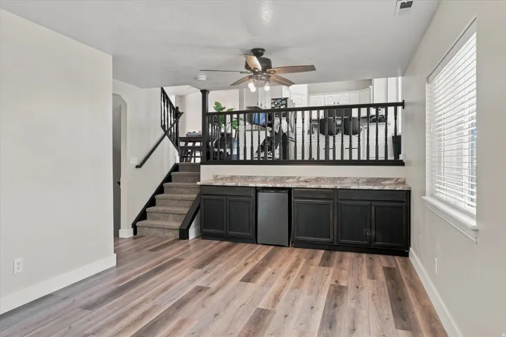 Wood-finish flooring, built-in cabinetry with a countertop, carpeted stairs with wood banisters, and a window with blinds