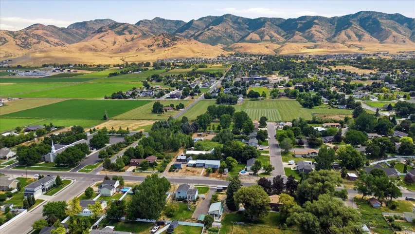 Expansive mountain backdrop, verdant agricultural fields, and established residential areas with mature trees