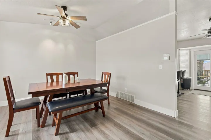 Vaulted ceiling with a ceiling fan, wood-finish flooring, and white trim work