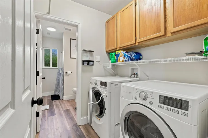Laundry area with wood-finish flooring, overhead cabinetry, and wire shelving
