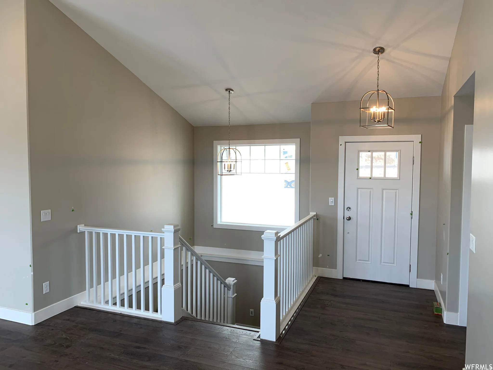 Entryway with wood-finish flooring, white paneled door, and a decorative pendant light fixture