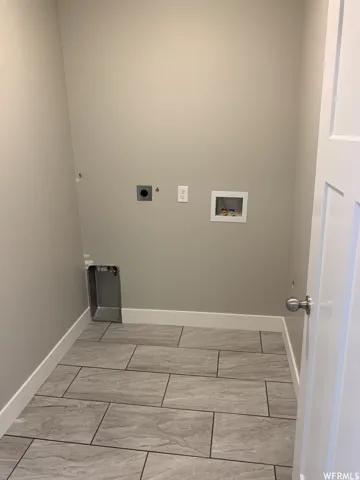 Laundry area featuring tile flooring, neutral wall paint, and utility hookups