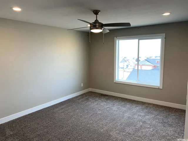 Recessed lighting, ceiling fan with integrated light, neutral wall tones, large window, and carpeted flooring