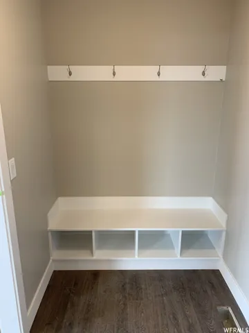 Built-in mudroom bench with cubby storage, equipped with wall-mounted coat hooks and wood-finish flooring