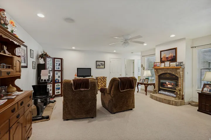 Built-in brick fireplace with a stone hearth, recessed lighting, and a ceiling fan