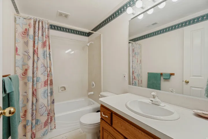 Spa-inspired bathroom featuring a wood-finish vanity with an oval white sink, white quartz countertop, and large framed mirror