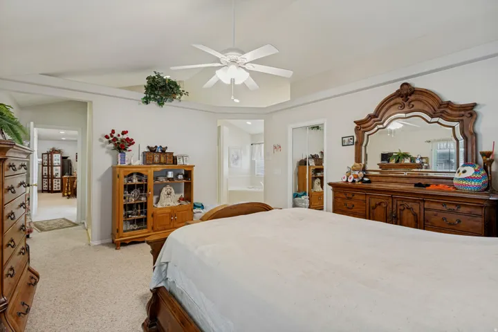Spacious primary bedroom suite showcasing hardwood furnishings, neutral carpeting, and abundant natural light from multiple windows