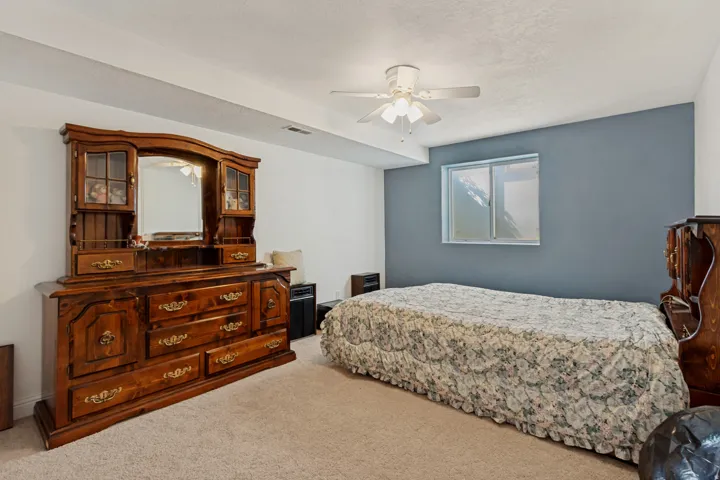 Spacious primary bedroom featuring neutral carpeting, a ceiling fan with integrated lighting, and an accent wall in soft blue-gray