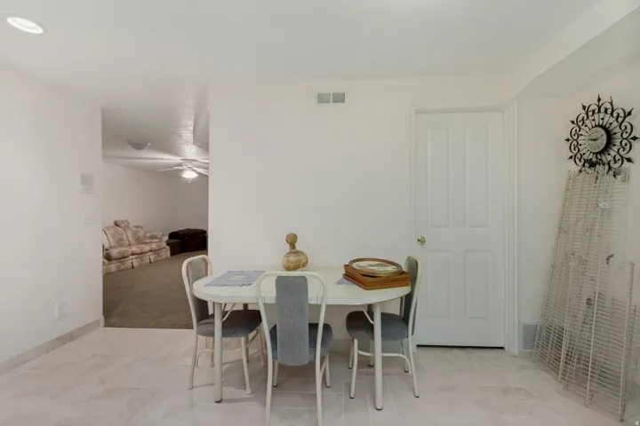 White interior walls and ceiling, recessed ceiling lighting, a white four-panel door, and tiled flooring