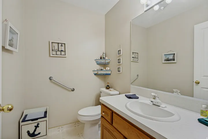 Spa-inspired bathroom featuring a wood-finish vanity with dual sink basins, white quartz countertop, and polished brass hardware