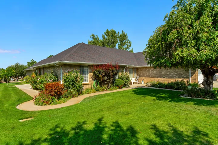 Brick exterior with a dark shingle roof, surrounded by mature landscaping and a concrete pathway