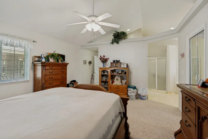 Vaulted ceiling with a ceiling fan, carpeted flooring, and a window with horizontal blinds