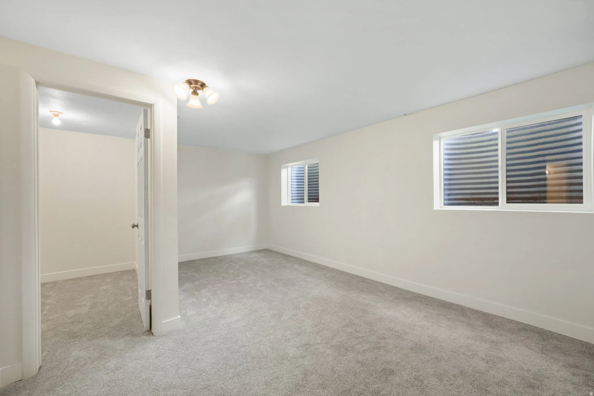 2nd Bedroom w/Walkin closet, Spacious room with light-colored carpeting, white painted walls, two egress windows, and a flush mount ceiling light fixture