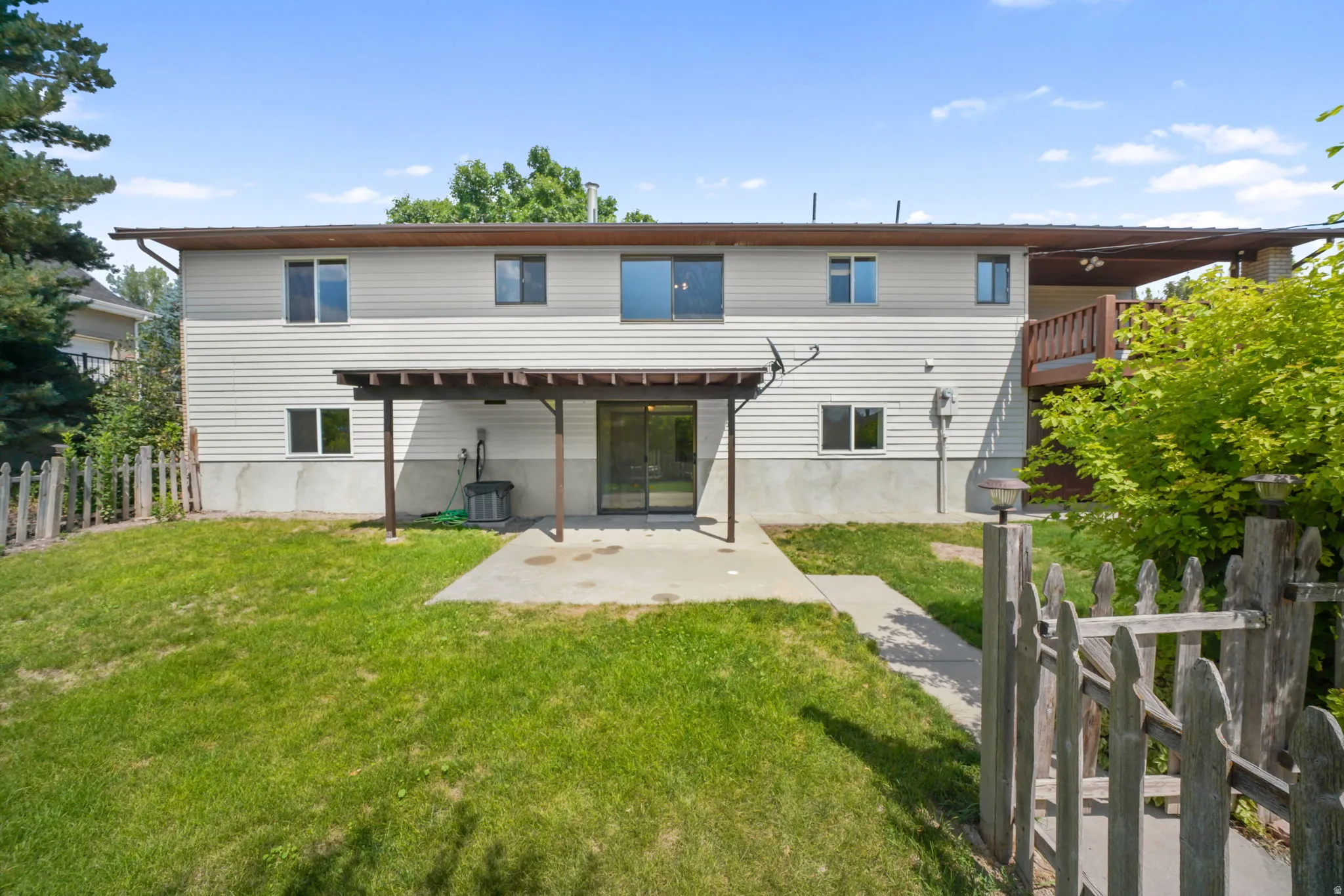 Rear of home, basement entrance thru covered patio,  upper-level balcony, and a fenced yard