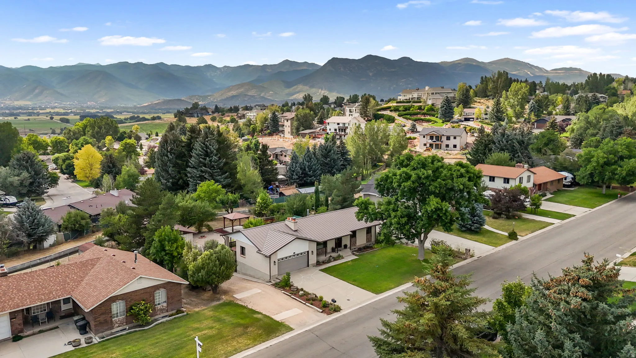 Expansive aerial view showcasing this residential property nestled within a verdant valley landscape
